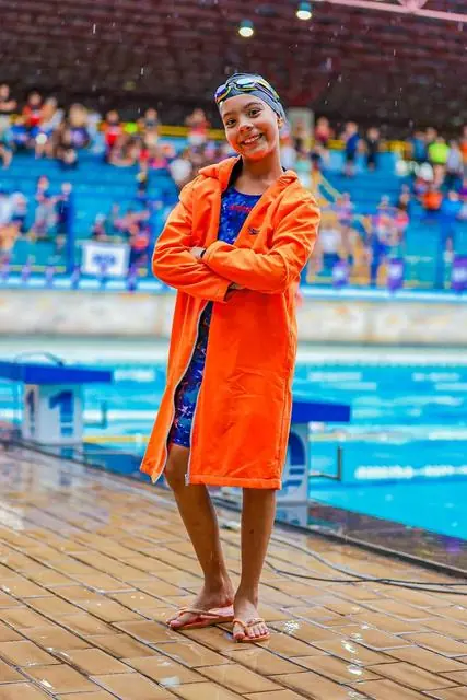 Lelê de roupão laranja na beira da piscina