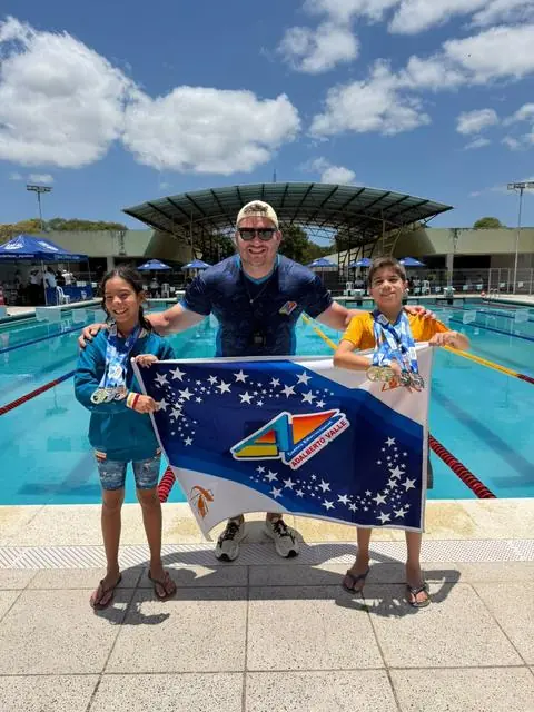 Lelê e colegas com a bandeira da equipe na piscina